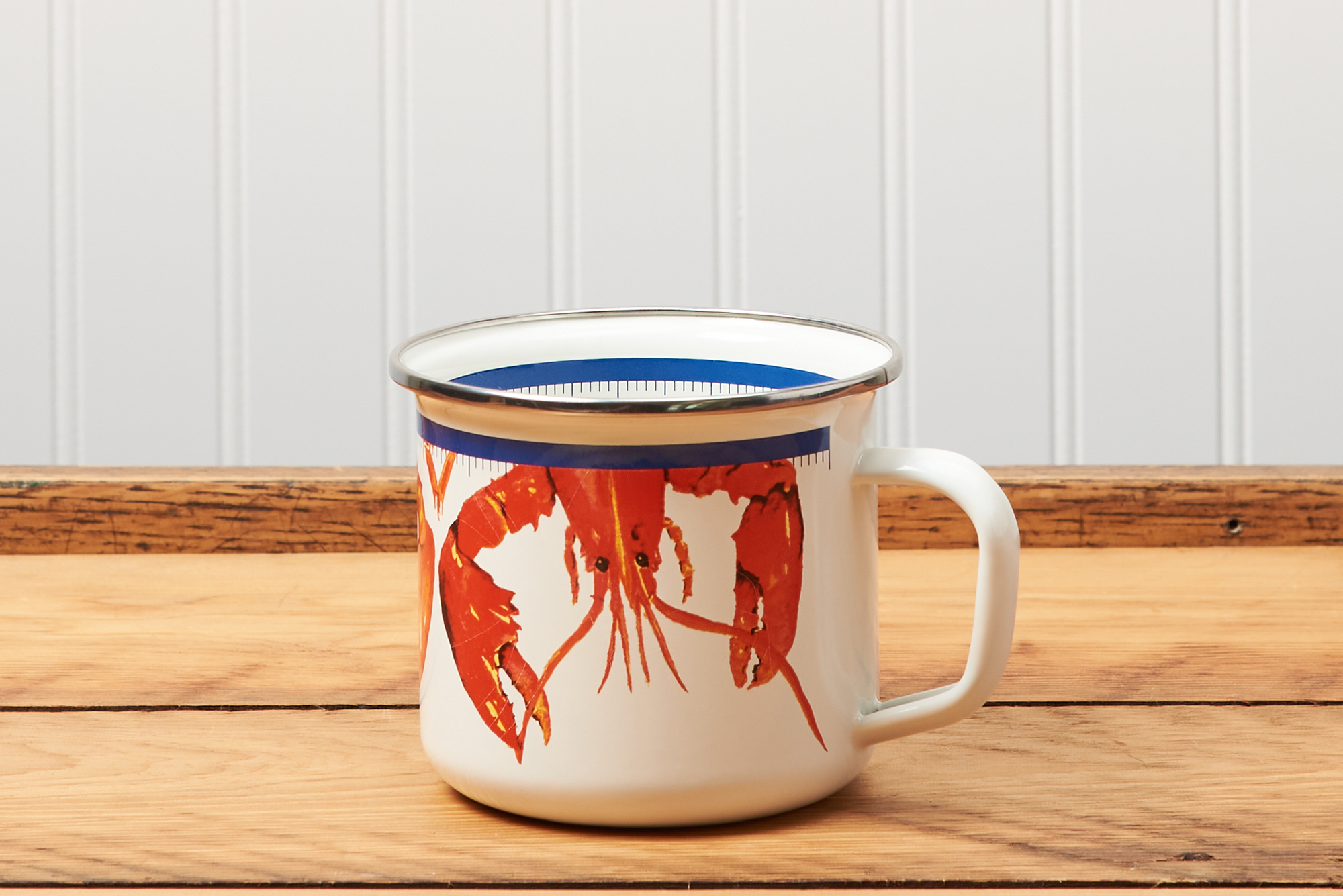 A Golden Rabbit Lobster Grande Mug sitting on a brown wooden table.