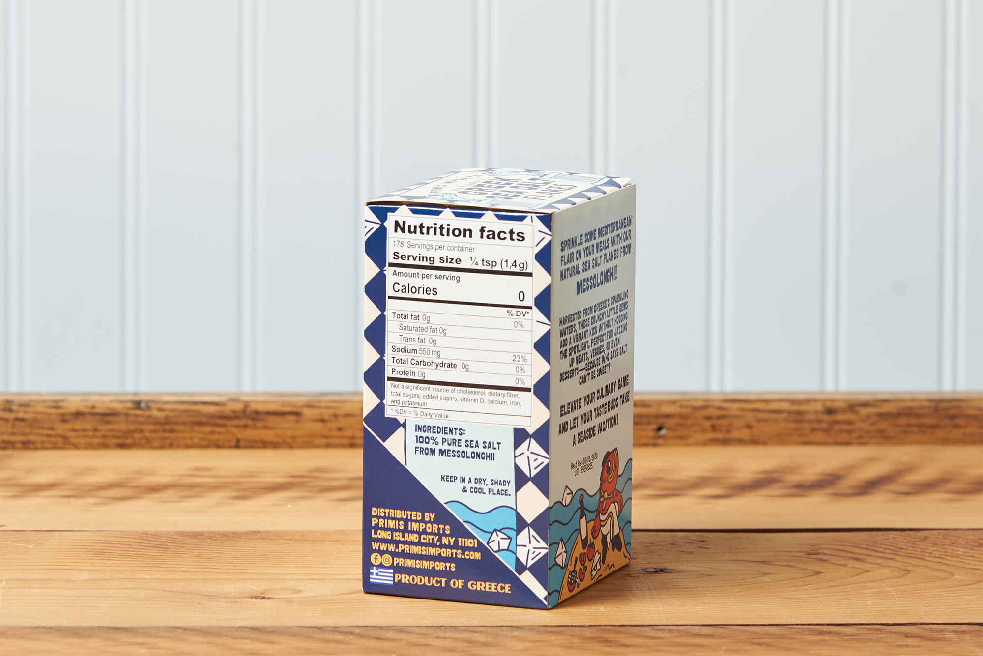 A side-facing view of a box of Greek Sea Salt Flakes sitting on a wooden table.