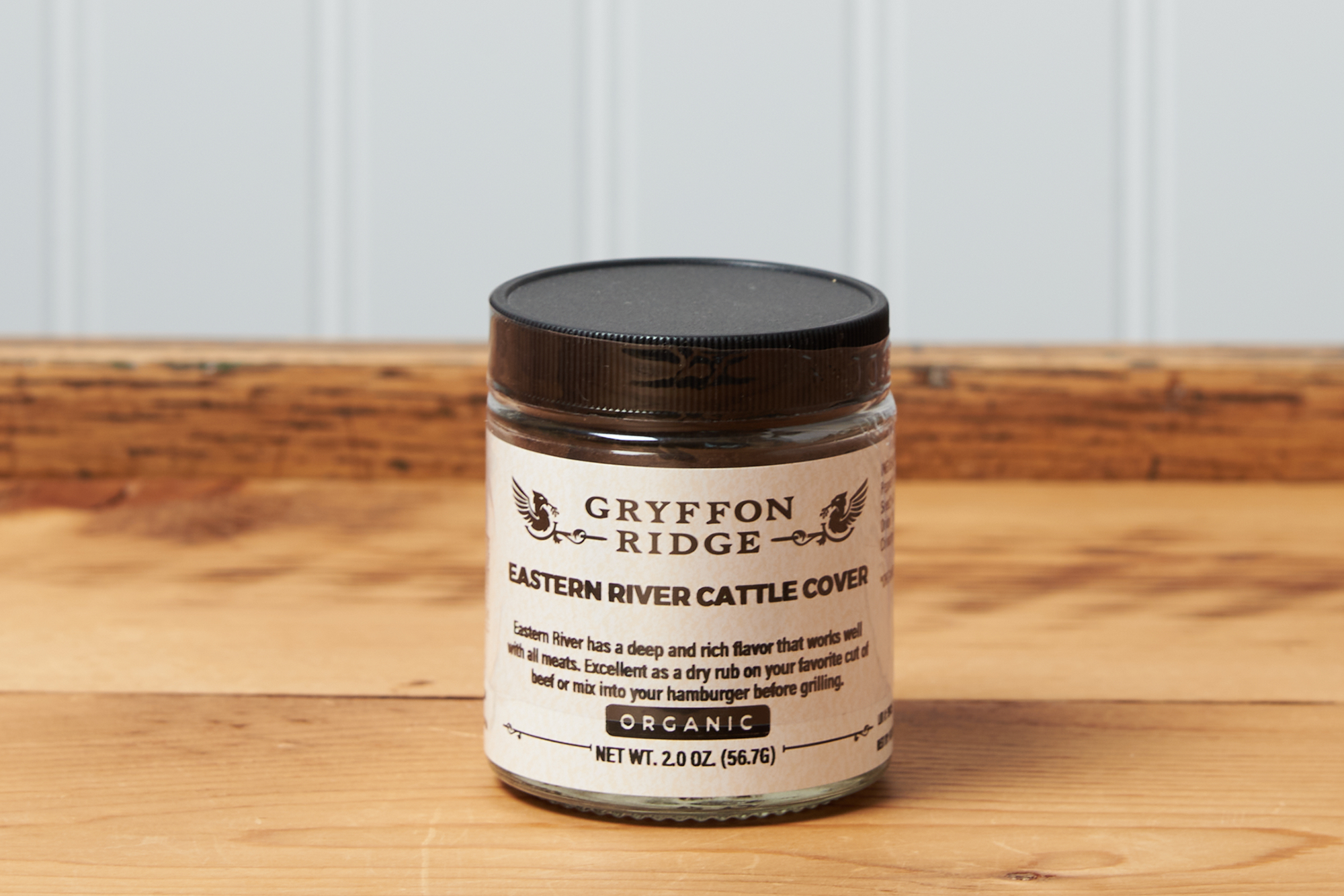 A jar of Gryffon Ridge Eastern River Cattle Cover sits on a wooden tabletop.