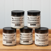 Five jars of Gryffon Ridge spices sit on a wooden tabletop. The spices include Eastern River Cattle Cover, Fire & Smoke, Northwoods Meat Rub, Moroccan Grilling Blend, and Rusty’s Rib Rub.