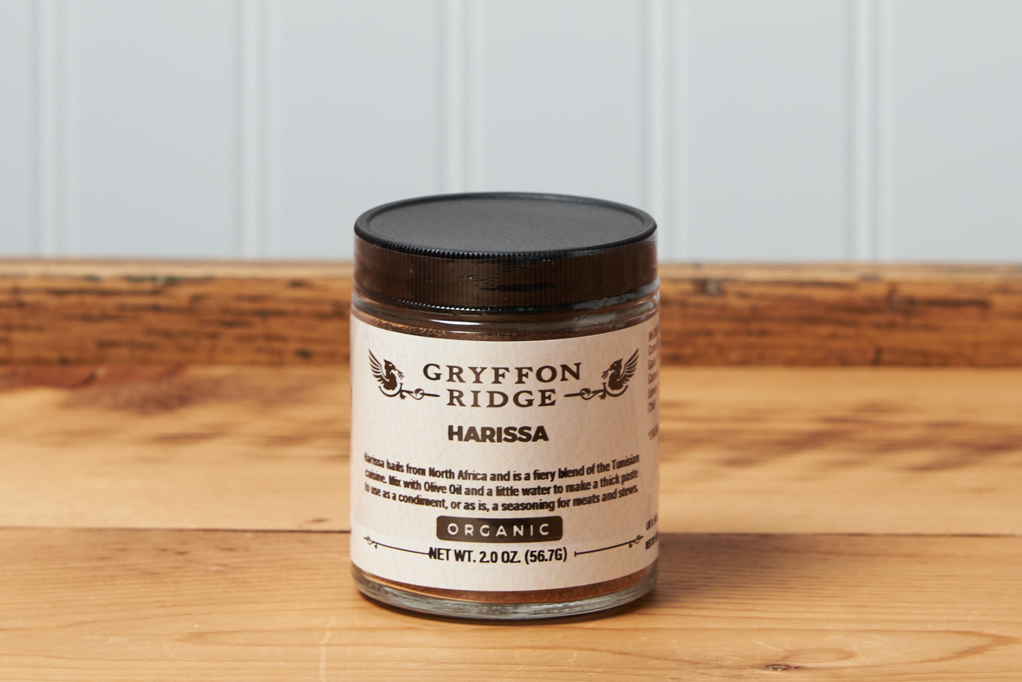 A jar of Gryffon Ridge Harissa sits on a wooden tabletop.