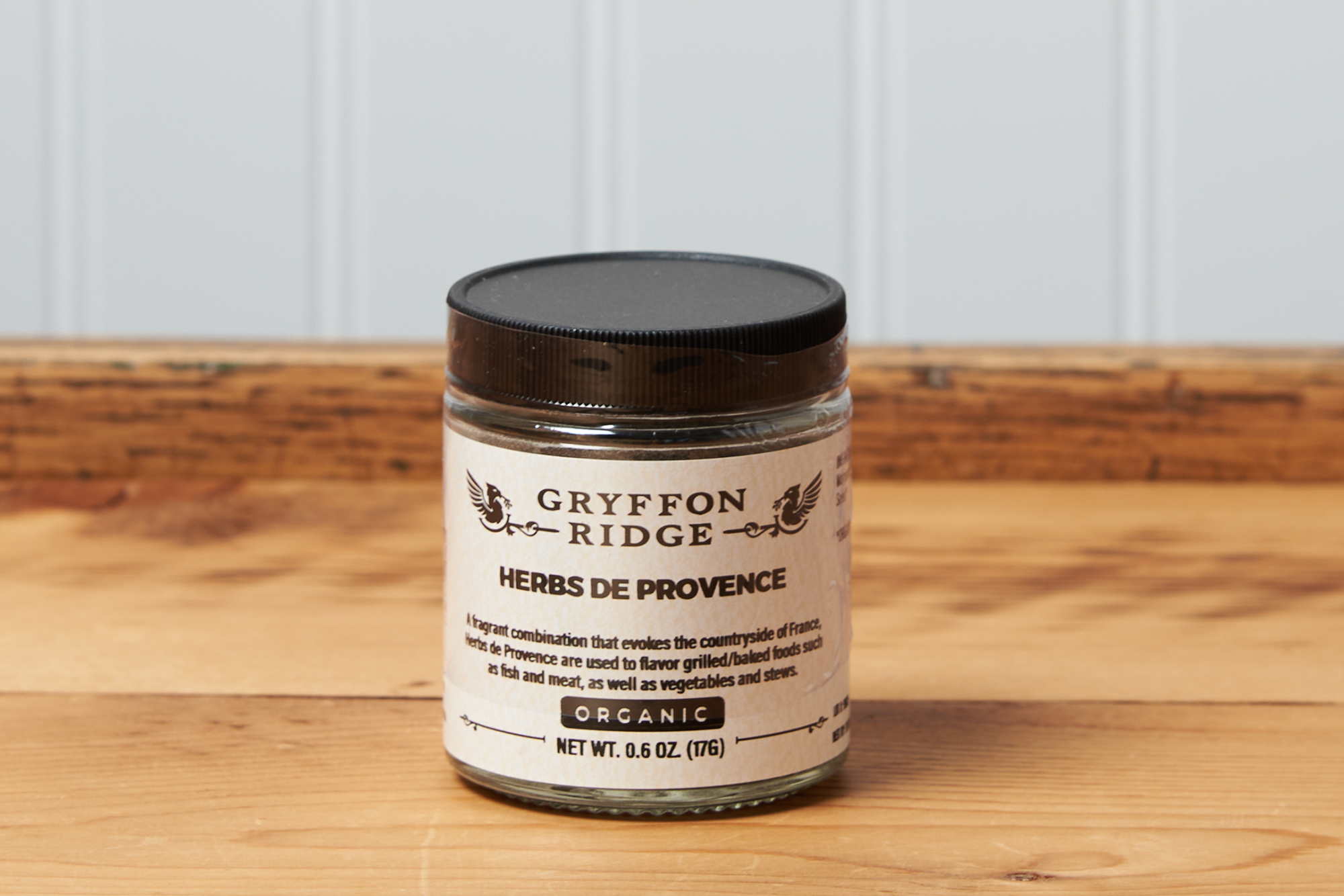 A jar of Gryffon Ridge Herbs de Provence sits on a wooden tabletop.