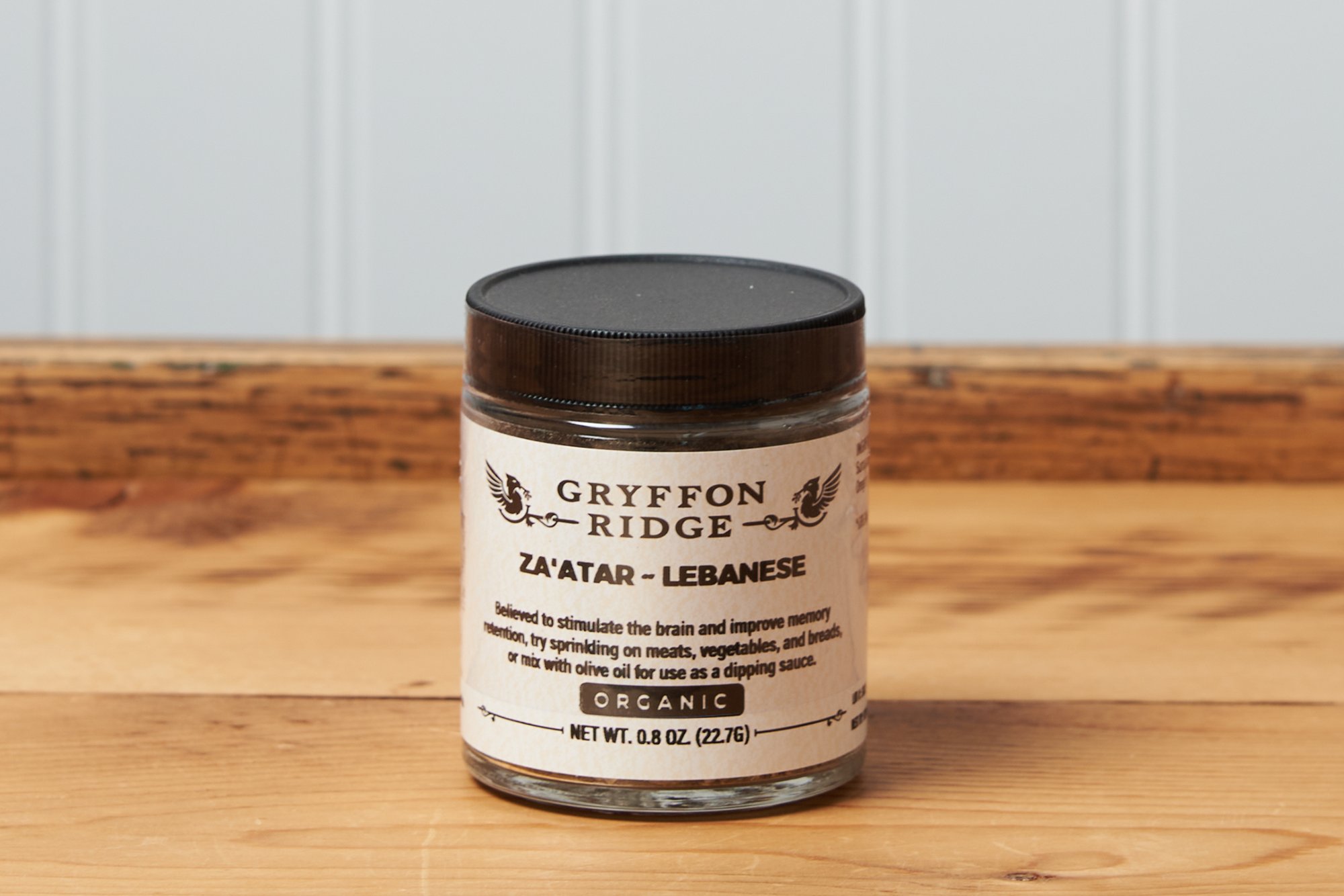 A jar of Gryffon Ridge Lebanese Za’atar sits on a wooden tabletop.