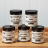 Five jars of Gryffon Ridge spices sit on a wooden tabletop. The spices include Tuscany Sunset, Harissa, Herbes de Provence, Lebanese Za’atar, and Duqqa