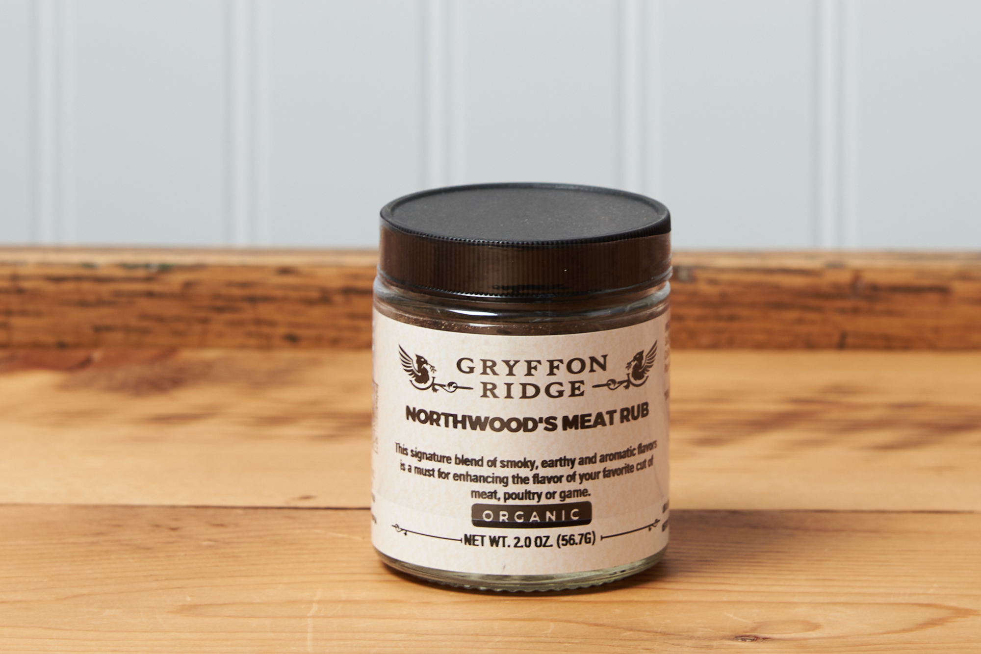 A jar of Gryffon Ridge Northwoods Meat Rub sits on a wooden tabletop.