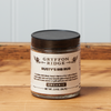 A jar of Gryffon Ridge Rusty’s Rib Rub sits on a wooden tabletop.