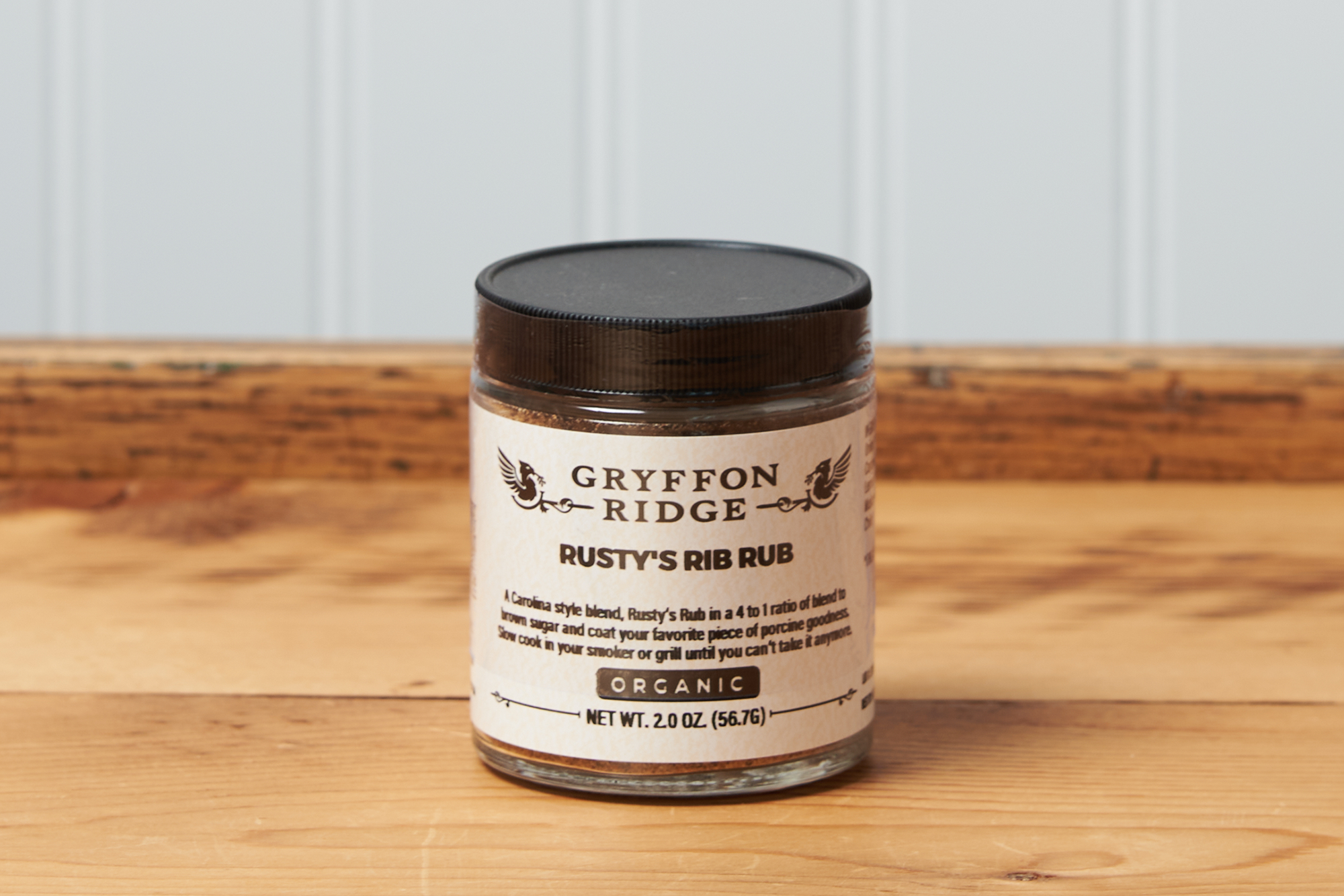 A jar of Gryffon Ridge Rusty’s Rib Rub sits on a wooden tabletop.