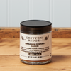 A jar of Gryffon Ridge Saigon Cinnamon Powder sits on a wooden tabletop.