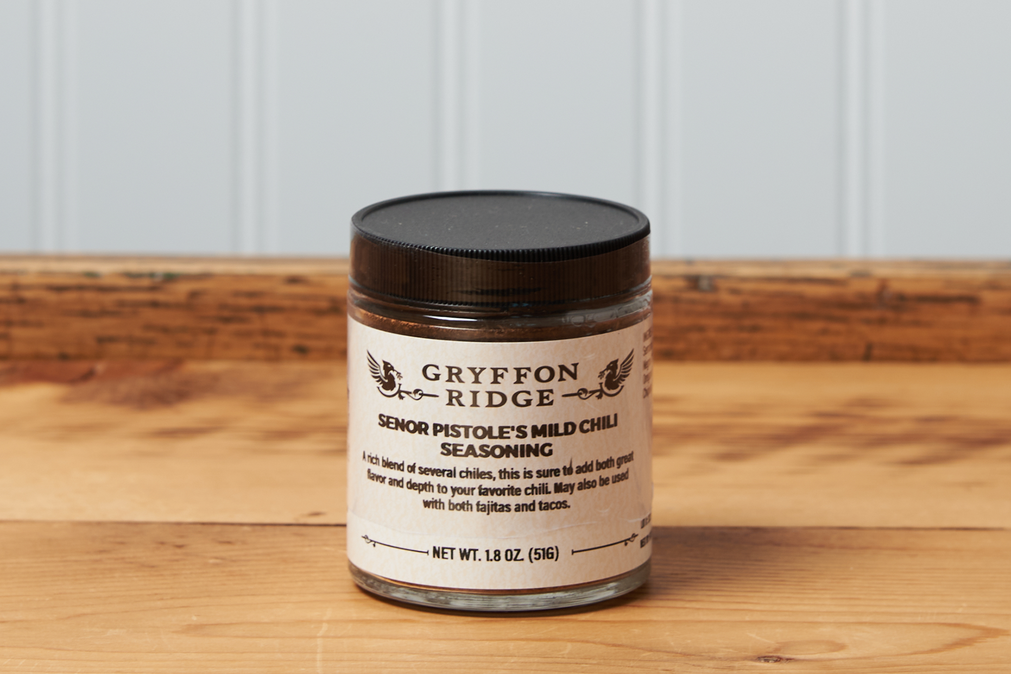 A jar of Gryffon Ridge Senor Pistole’s Mild Chili Seasoning sits on a wooden tabletop.