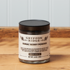 A jar of Gryffon Ridge Sumac Berry Powder sits on a wooden tabletop.