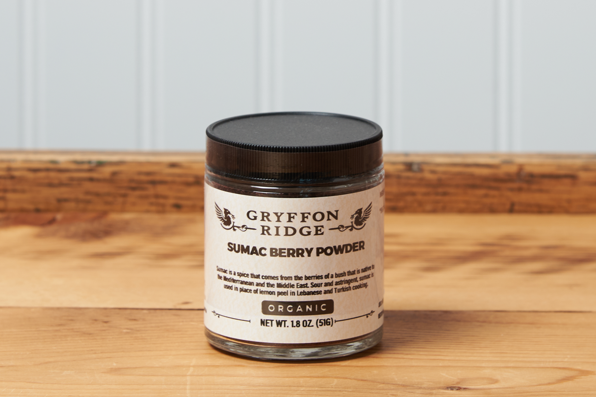 A jar of Gryffon Ridge Sumac Berry Powder sits on a wooden tabletop.