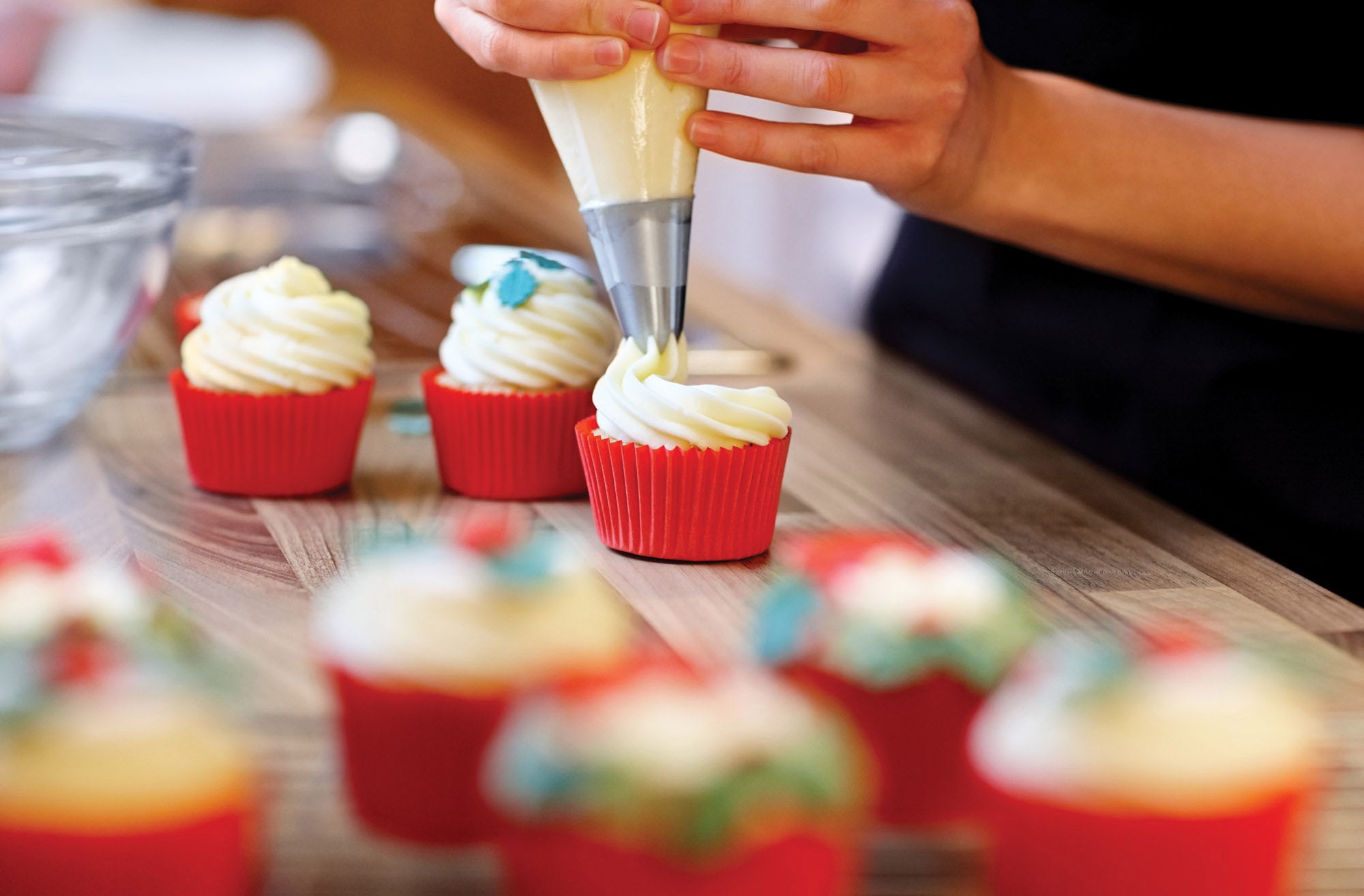 Person frosting cupcakes using Mrs. Anderson's Baking Pastry Decorating Tips.