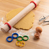 Rolling pin with Mrs. Anderson's Baking Silicone Rolling Pin Rings on rolled-out dough on a wooden surface with flour.