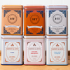 An assortment of Harney & Sons tea sits on a wooden countertop. The assortment includes the following teas: Hot Cinnamon Sunset, Paris, Vanilla Comoro, Earl Grey Supreme, English Breakfast, and Peaches and Ginger