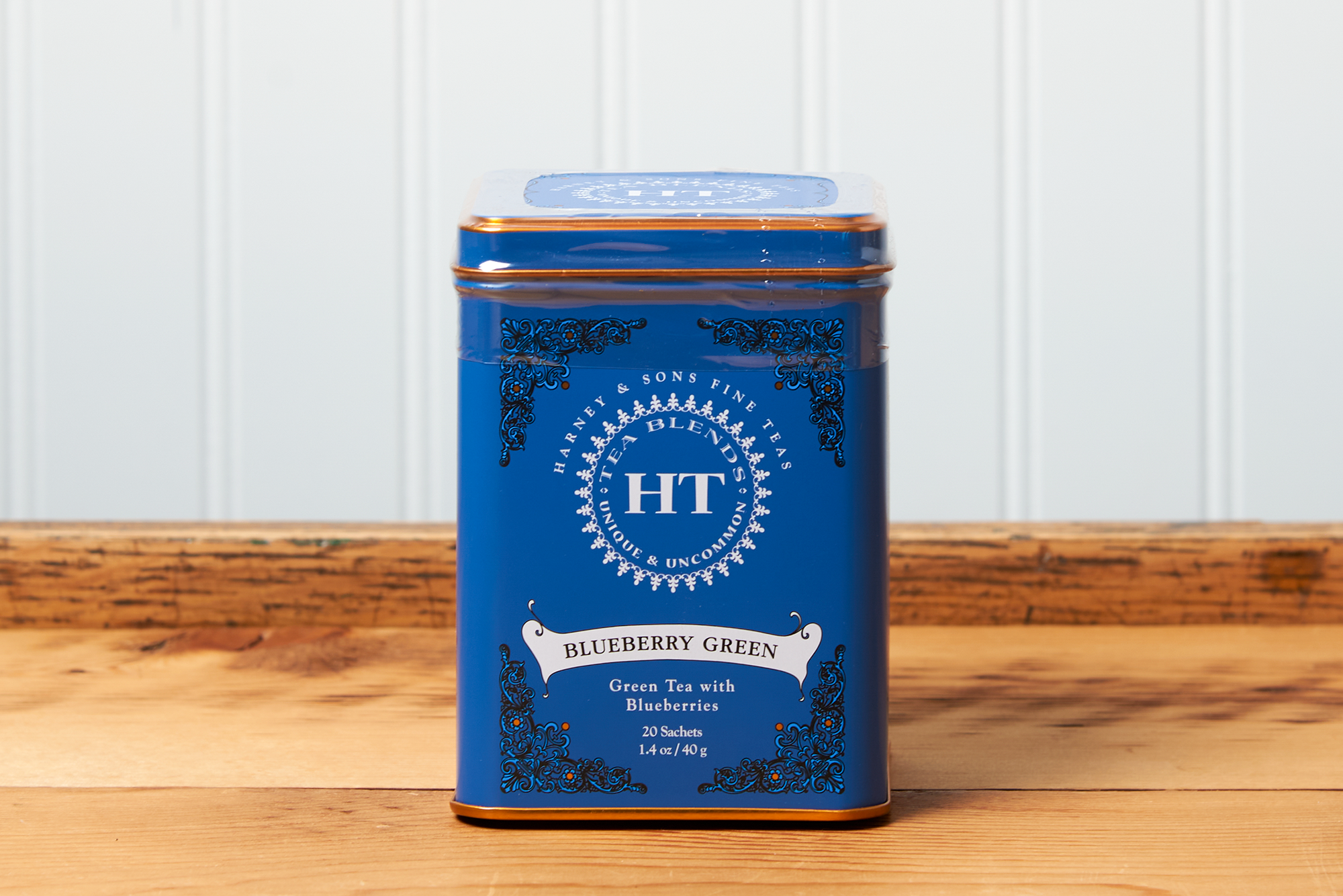 A tin of Harney & Sons Blueberry Green tea sits on a wooden countertop.