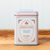 A tin of Harney & Sons Earl Grey Supreme tea sits on a wooden countertop.