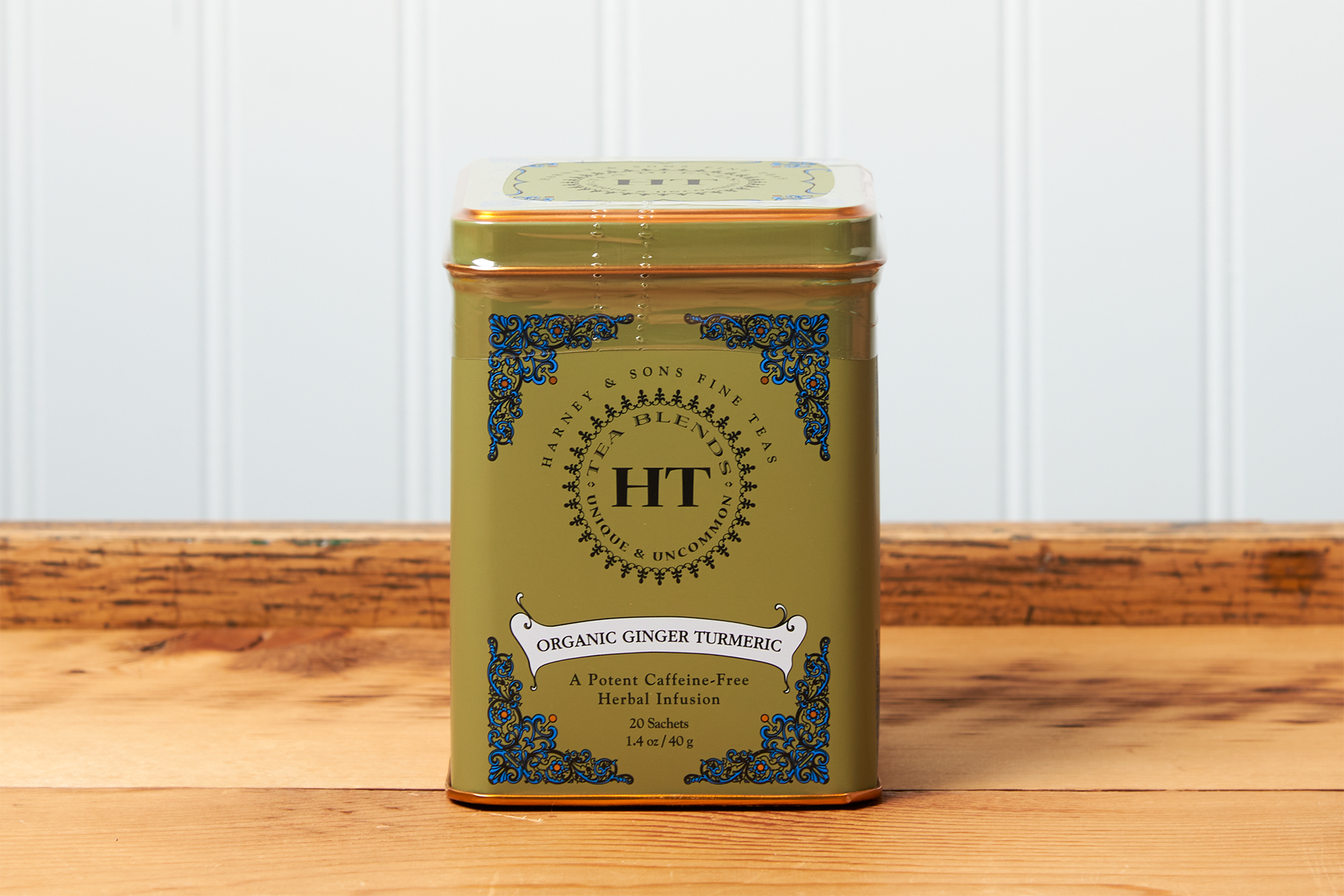 A tin of Harney & Sons Ginger Turmeric tea sits on a wooden countertop.