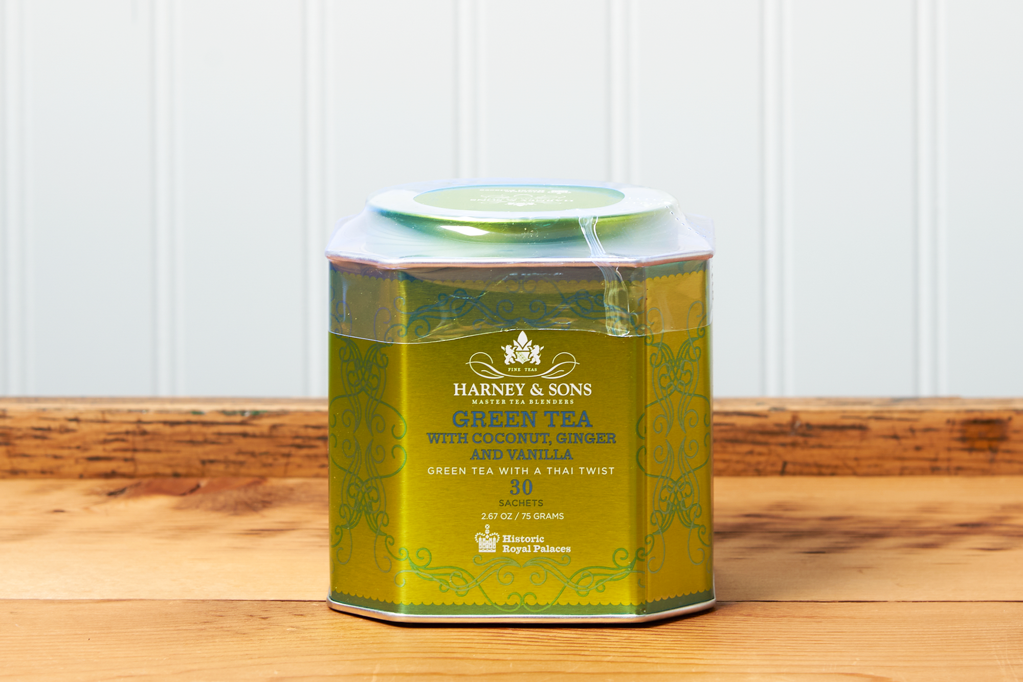 A tin of Harney & Sons Green Tea with Coconut tea sits on a wooden countertop.