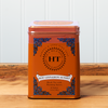 A tin of Harney & Sons Hot Cinnamon Sunset tea sits on a wooden countertop.