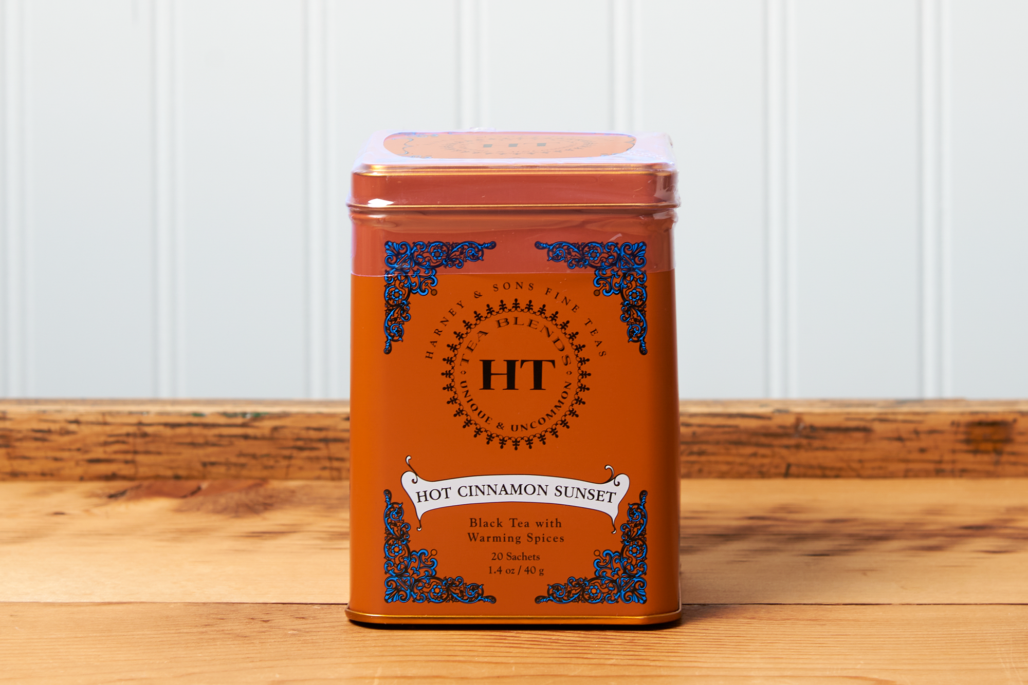 A tin of Harney & Sons Hot Cinnamon Sunset tea sits on a wooden countertop.