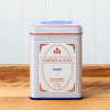 A tin of Harney & Sons Paris tea sits on a wooden countertop.
