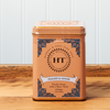 A tin of Harney & Sons Peaches and Ginger tea sits on a wooden countertop.