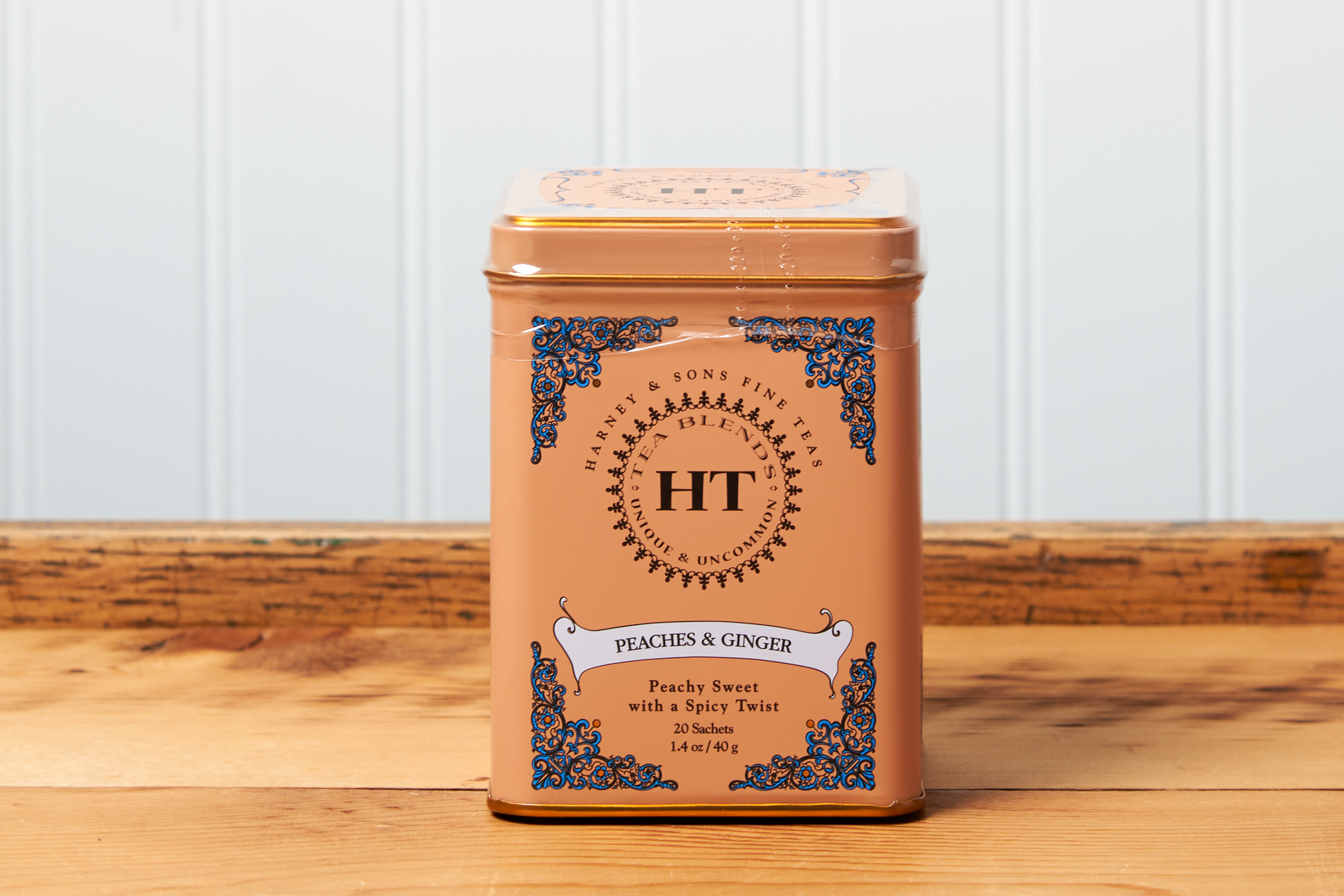 A tin of Harney & Sons Peaches and Ginger tea sits on a wooden countertop.