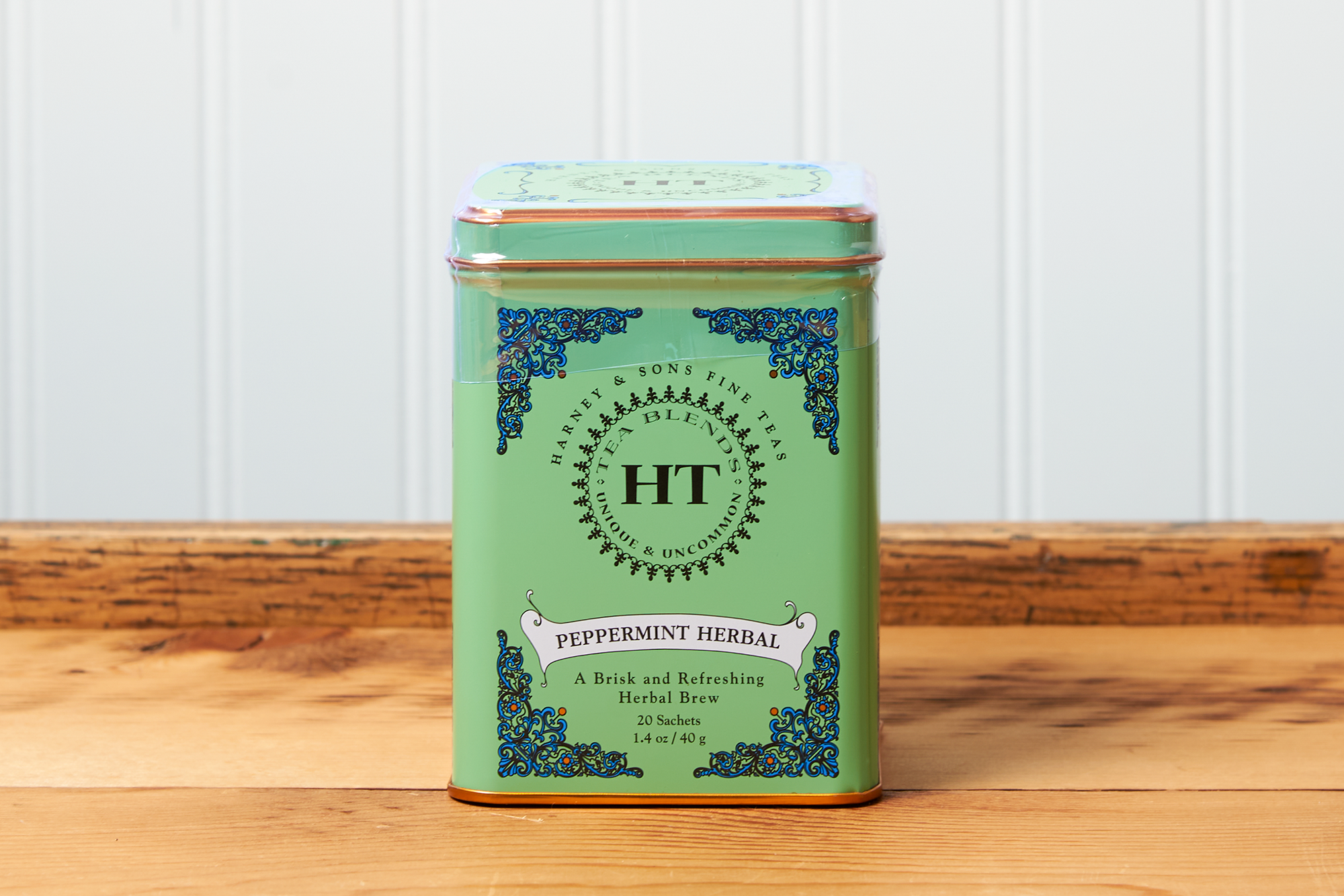 A tin of Harney & Sons Peppermint Herbal tea sits on a wooden countertop.