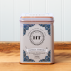 A tin of Harney & Sons Vanilla Comoro tea sits on a wooden countertop.