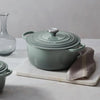 A Le Creuset Signature Round Oven in Sea Salt color sits on a marble countertop.