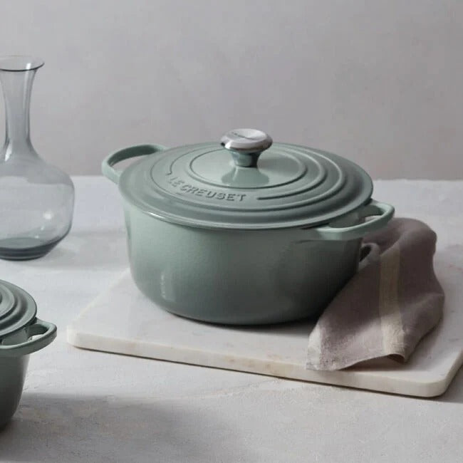 A Le Creuset Signature Round Oven in Sea Salt color sits on a marble countertop.