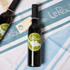 Two LeRoux Jacquard Towels lay underneath two bottles of olive oil and balsamic vinegar.