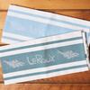 Two LeRoux Jacquard Towels on a brown wooden table.