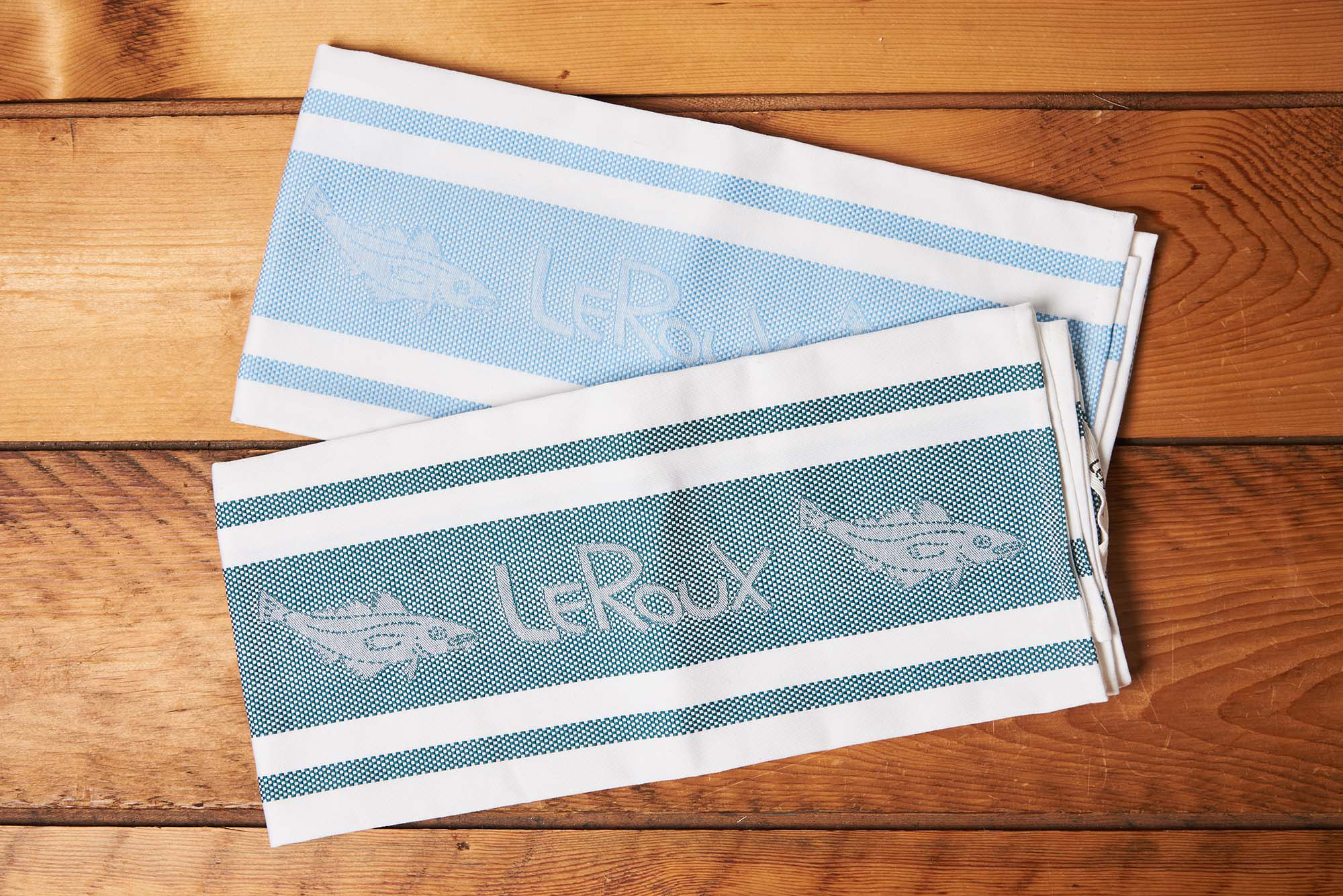 Two LeRoux Jacquard Towels on a brown wooden table.