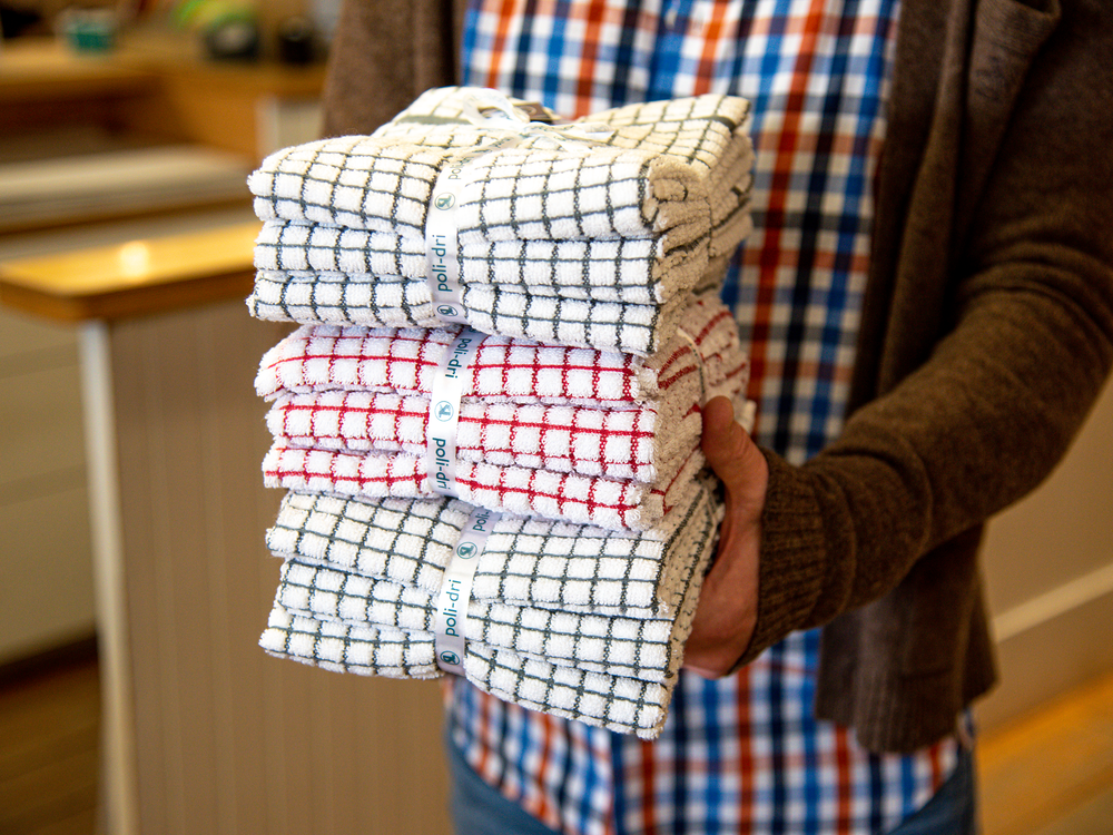A staff member holds a stack of patterned towels.