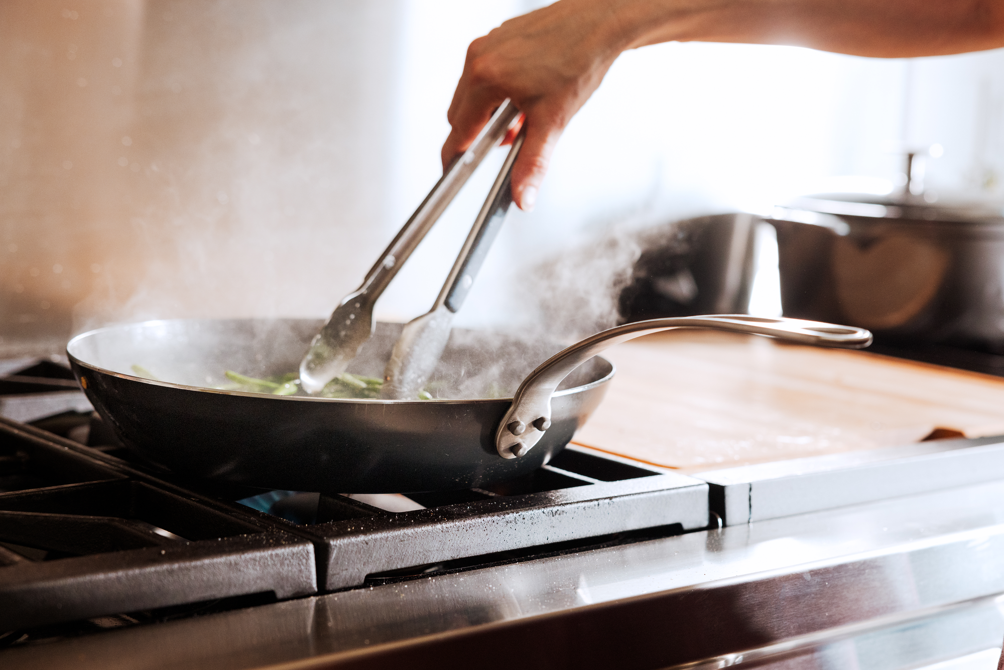 A person cooks green beans in a Made In Seasoned Carbon Steel Fry pan.