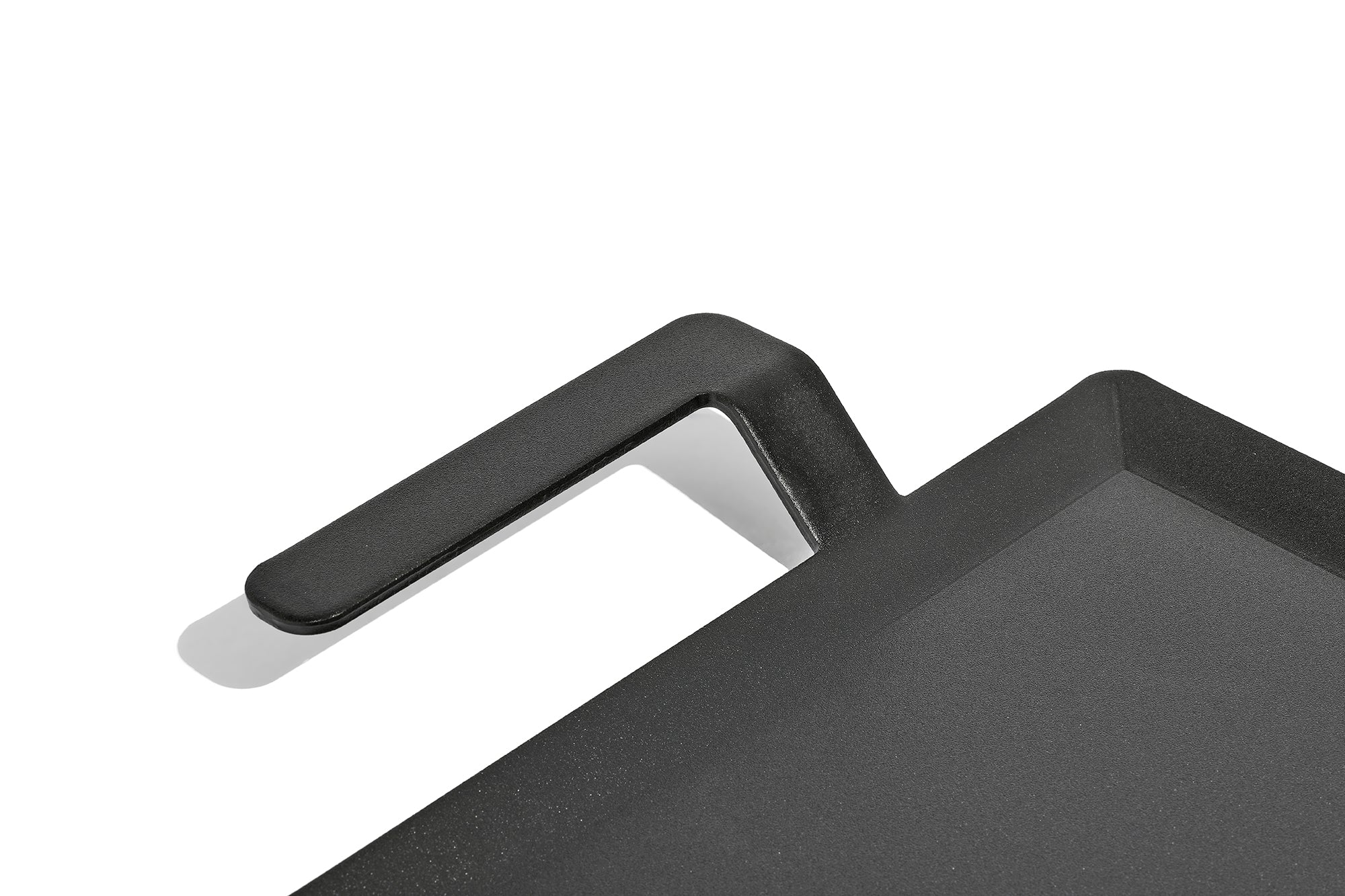 A close up on the handle of a Made In Seasoned Carbon Steel Griddle in front of a white background.