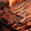 Bacon is cooked in a firepit on a Made In Seasoned Carbon Steel Griddle.