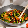 A person stir fries vegetables in a Made In Seasoned Carbon Steel Wok.