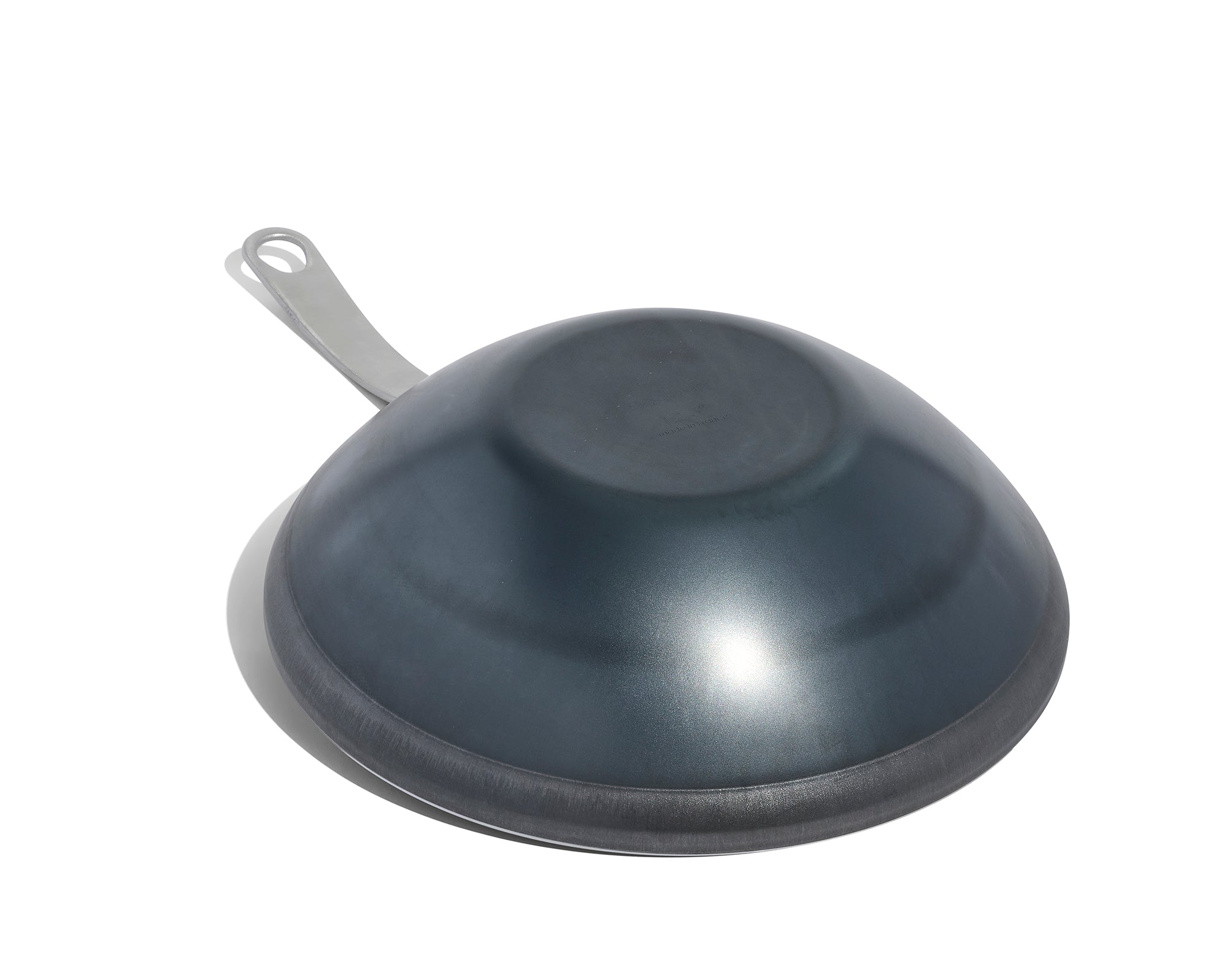 An upside down Made In Seasoned Carbon Steel Wok in front of a white background.