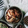 A Made In Stainless Clad Saucepan full of spiced apples sits on a tablespread. Alongside the saucepan are other dishes, including a plate of waffles.