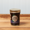 A jar of Maine Homestead Wild Maine Blueberry Jam sits on a brown wooden table.