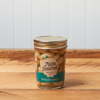A jar of Maine Homestead Pickled Garlic sits on a brown wooden table.