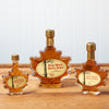 Three Maine Maple Syrup maple leaf jars sit on a brown wooden table.
