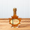 A 100ml Maine Maple Syrup maple leaf jar sits on a brown wooden table.