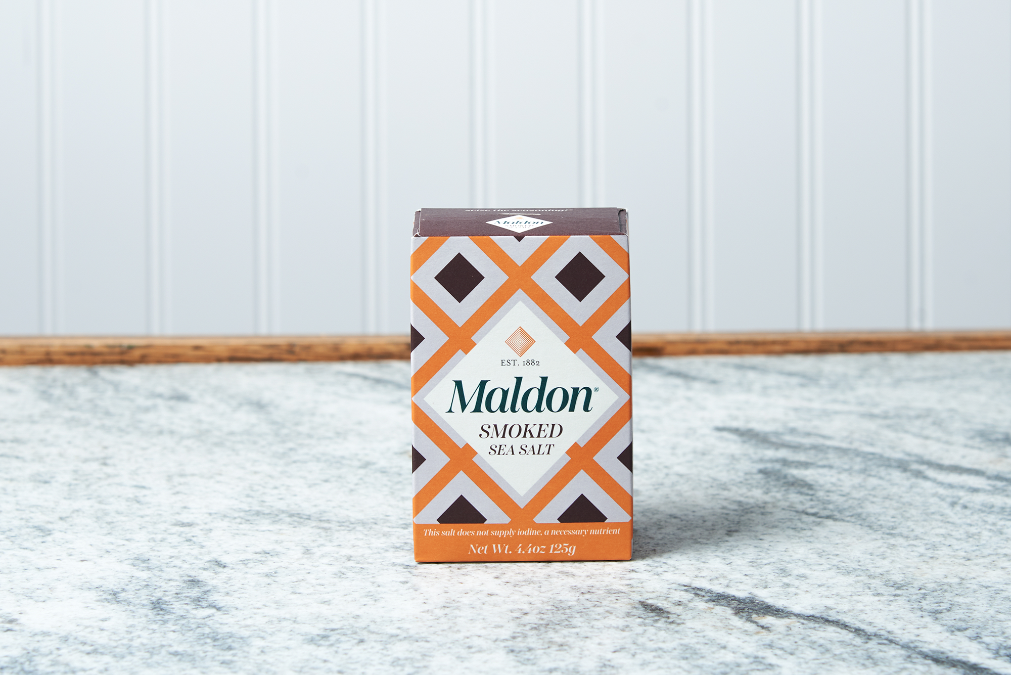 A box of Maldon Smoked Sea Salt Flakes sits on a marble countertop.