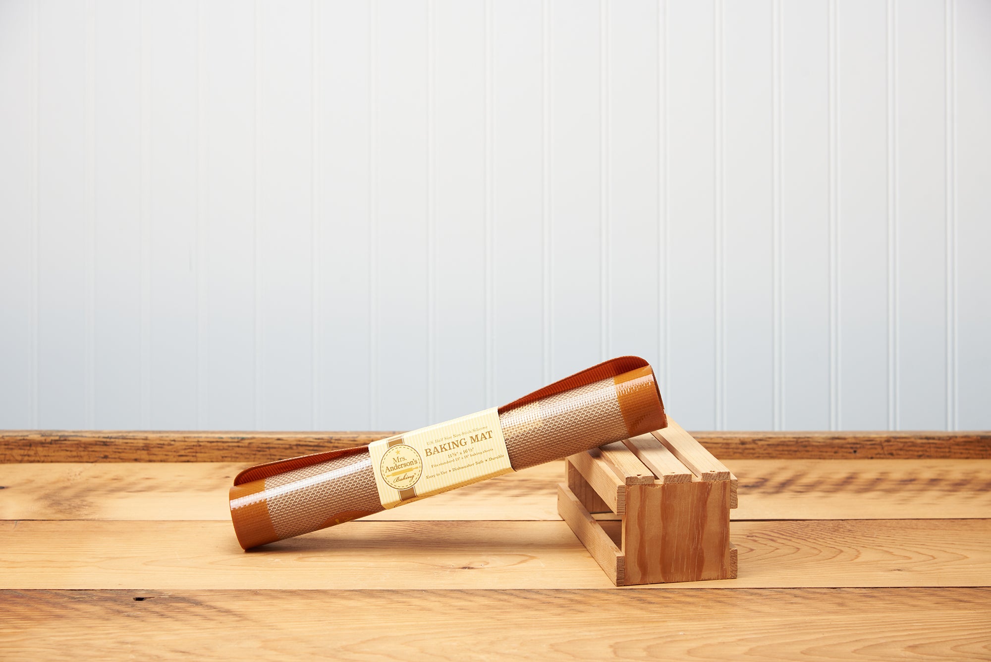 A Mrs. Anderson's Half Size Silicone Baking Mat is perched on a small wooden crate upon a wooden tabletop.