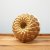A Nordic Ware Kaleidoscope Bundt Pan sits on a brown, wooden table.