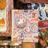 The cookbook 'Delectable: Sweet & Savory Baking' sits on a shelf alongside an assortment of kitchen gadgets and textiles.
