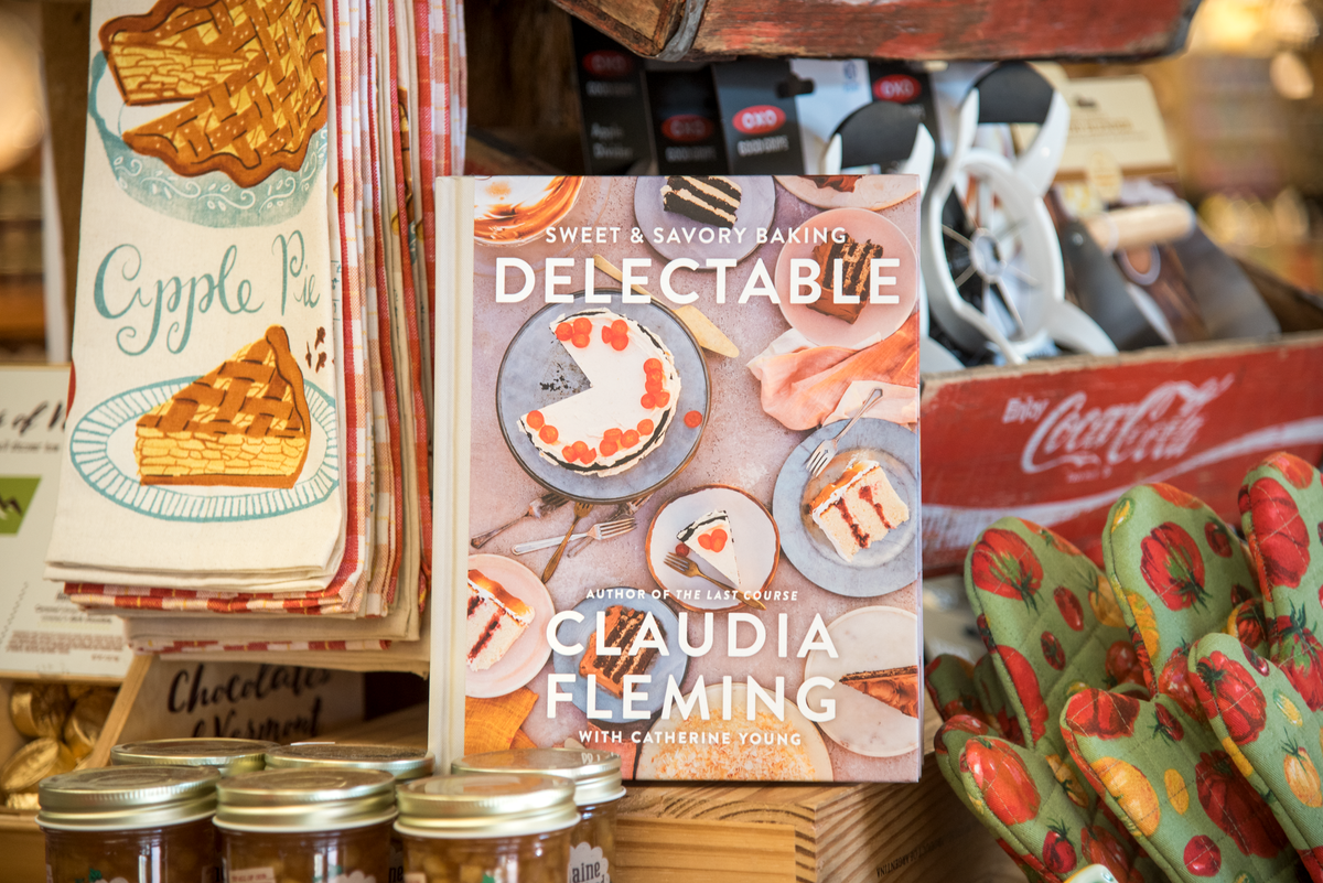 The cookbook 'Delectable: Sweet & Savory Baking' sits on a shelf alongside an assortment of kitchen gadgets and textiles.